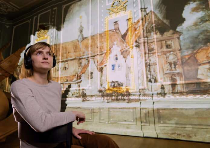 Persoon met koptelefoon op kijkt naar projecties van huizen op wanden