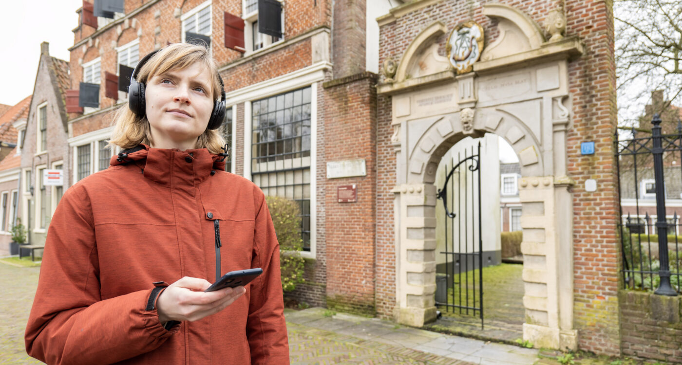 Persoon met koptelefoon en mobiel voor monumentale poort