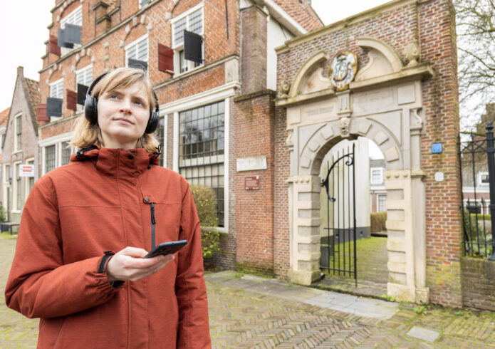 Persoon met koptelefoon en mobiel voor monumentale poort