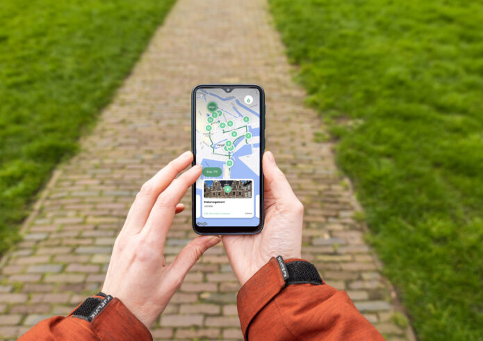 Twee handen houden mobiel vast met wandelroute erop