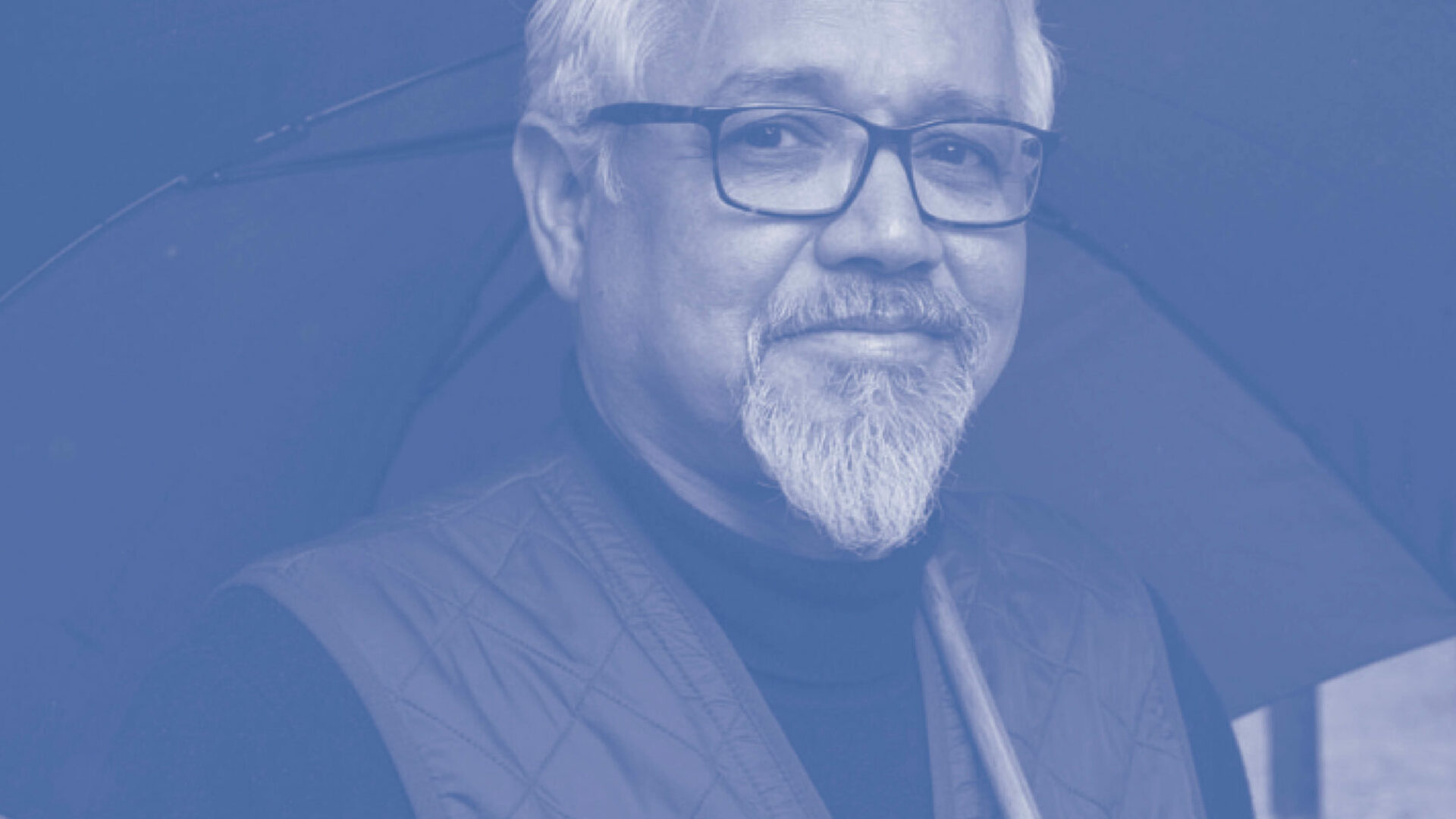 Portret Amitav Ghosh, met bril en paraplu