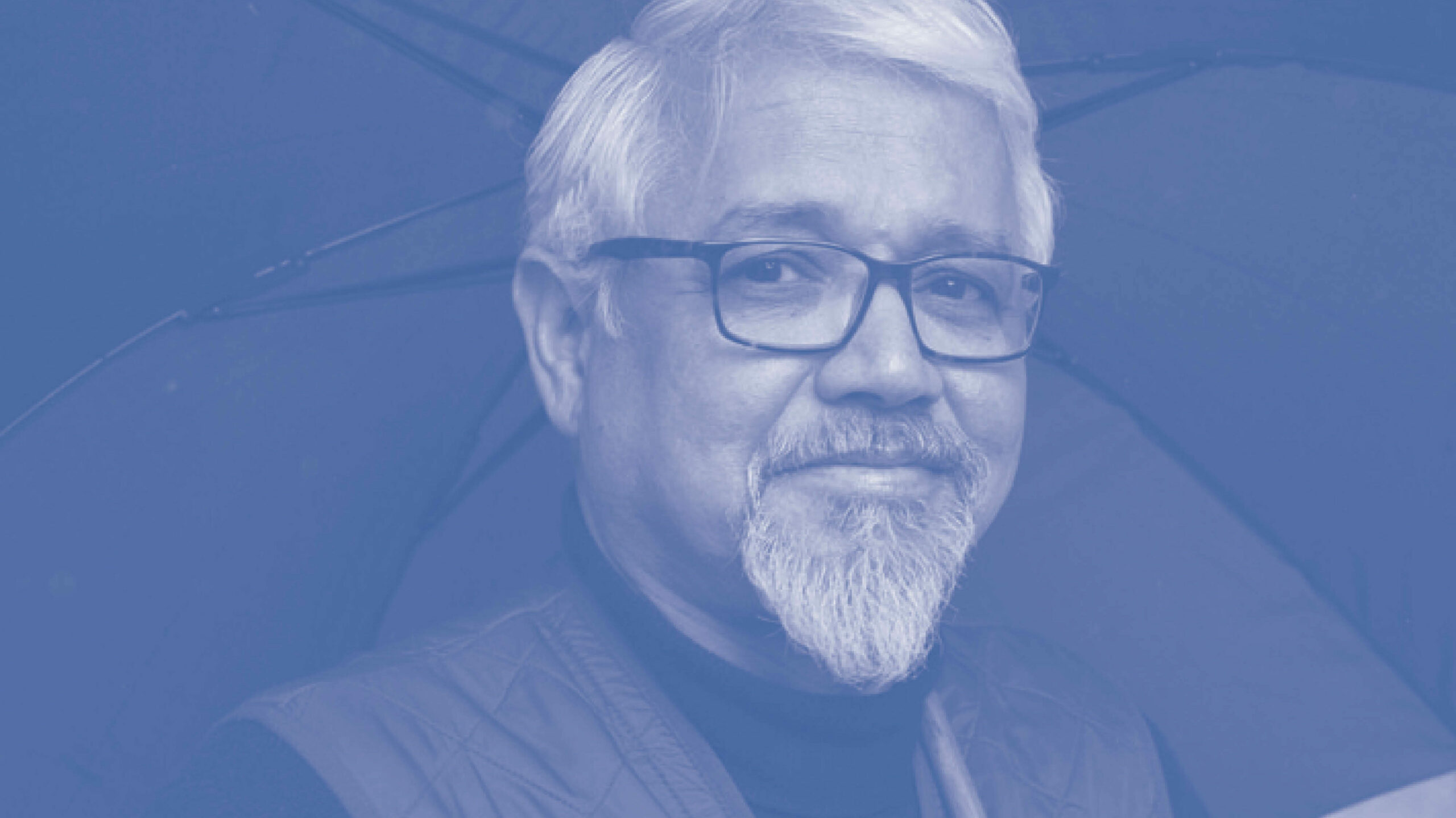 Portret Amitav Ghosh, met bril en paraplu