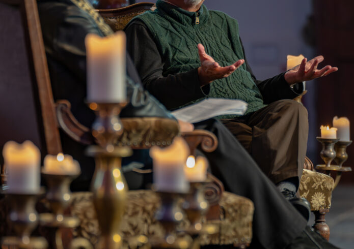 Twee personen in gesprek op klassieke stoelen met kaarsen eromheen